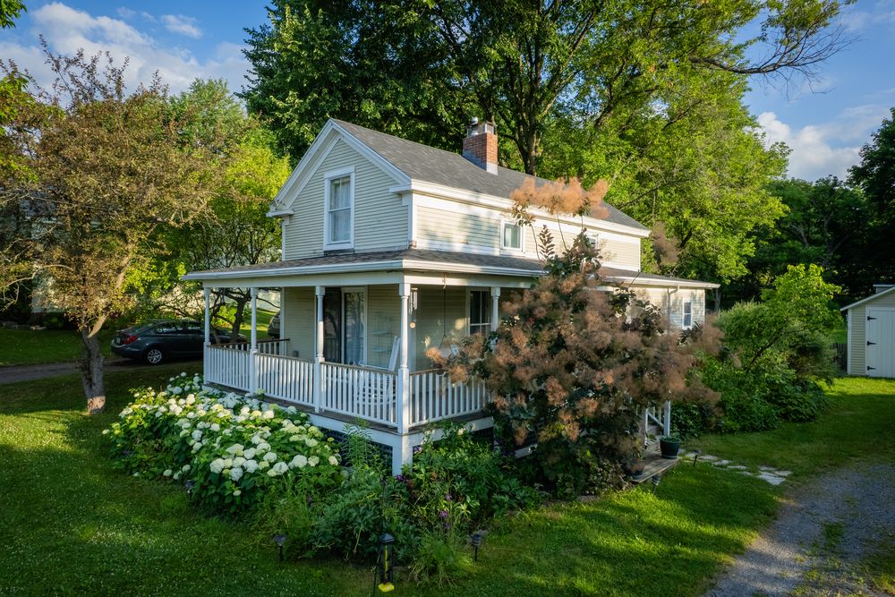 Farmhouse with a wraparound porch and shingle roof in Monkton, Vermont