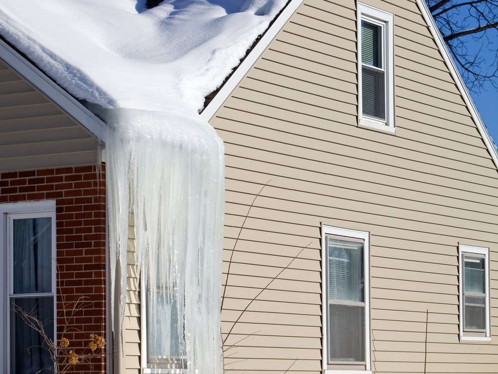 Ice dam and icicles along the eave of a Vermont home in winter